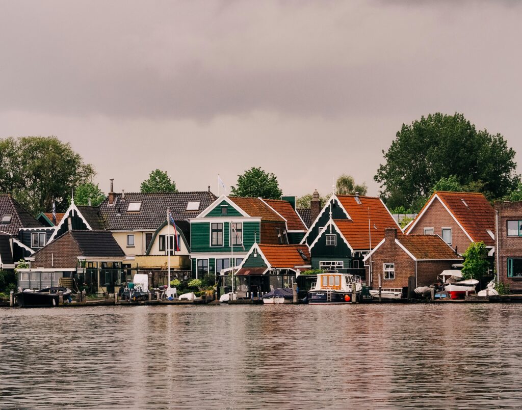 Luxury Villas and Bungalows Scenic view of traditional Dutch houses along a canal under an overcast sky.
